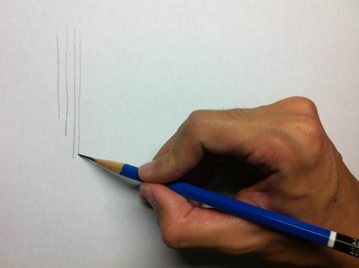 鉛筆持ちで縦の線を描く